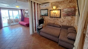 Una sala de estar con un sofá marrón, un televisor de pantalla plana y una lámpara de pared.