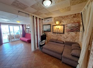 Ein Wohnzimmer mit einem braunen Sofa, einem Flachbildfernseher und einer Wandlampe.