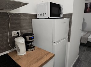 A compact kitchenette with a white refrigerator, a microwave, a coffee maker, and a power outlet on a wooden countertop. - Apartments Tourist Port - Studio Apartment with Balcony (Dubrovnik)