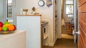 Una cocina compacta con encimera de madera, un frutero y un reloj en la pared.