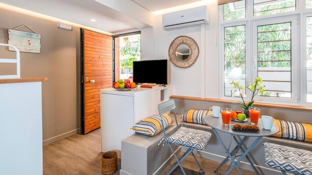 Una habitación moderna con televisión, zona de estar y espacio para el desayuno.