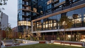 Un edifici modern amb façana de vidre, zones d'estar a l'exterior i un jardí ben cuidat.