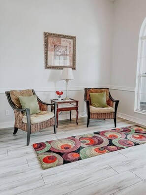 Une pièce comprenant deux fauteuils, une petite table, une lampe et un tapis à motifs.