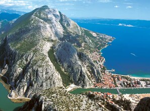 A mountainous landscape with a coastal town at its base. - Apartment Almira - One bedroom apartment with sea view (Omis)