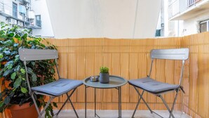 A small outdoor seating area with two foldable chairs and a table, surrounded by a bamboo fence. - Roubnb Acropolis Museum 1BD Apt (Athina)