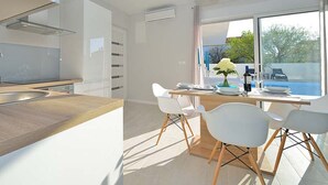 Une cuisine moderne avec un plan de travail en bois et des chaises blanches.