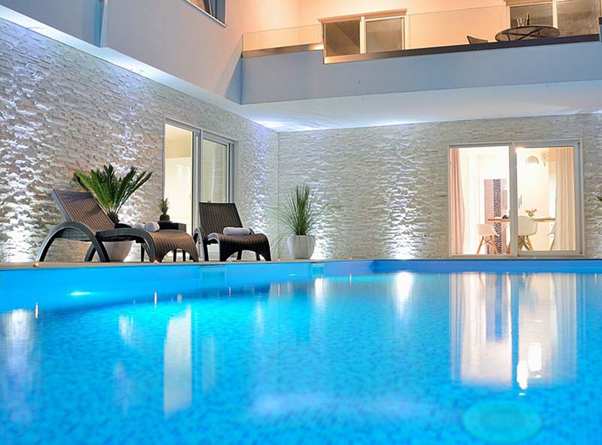 Une piscine avec des chaises longues et des plantes en pot.