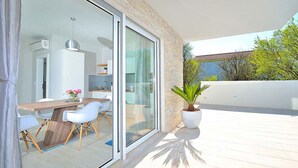 Un balcón moderno con zona de comedor, una planta en maceta y vistas del paisaje circundante.