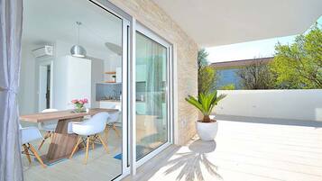 A modern balcony with a dining area, a potted plant, and a view of the surrounding landscape.
