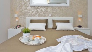 Une chambre à coucher avec un lit, des tables de chevet, un plateau avec des tasses et de la nourriture, et un miroir au mur.