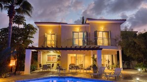 A two-story house with a swimming pool, outdoor seating, and a balcony. - Latchi Aria Villa in Latchi (Latchi)