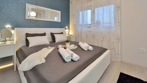 Ein Schlafzimmer mit einem Bett, Nachttischen, einem Spiegel und einem Fenster mit Vorhängen.