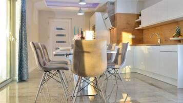 A modern kitchen with white cabinets, a dining area with a table and chairs, and a large window with curtains.