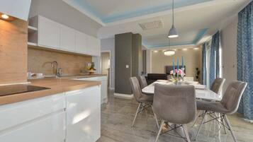 A modern kitchen with white cabinets, a wooden countertop, and a dining area with a table and chairs.
