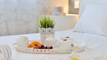A neatly arranged breakfast tray with pastries, a cup, and a small potted plant on a bed.