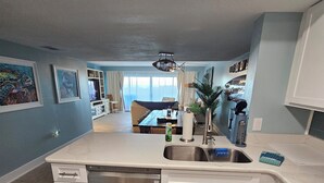 Cozinha moderna com armários brancos, máquina de lavar louça embutida e uma ilha grande com pia.