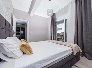 Ein modernes Schlafzimmer mit Bett, Kleiderschrank und Blick ins Freie.