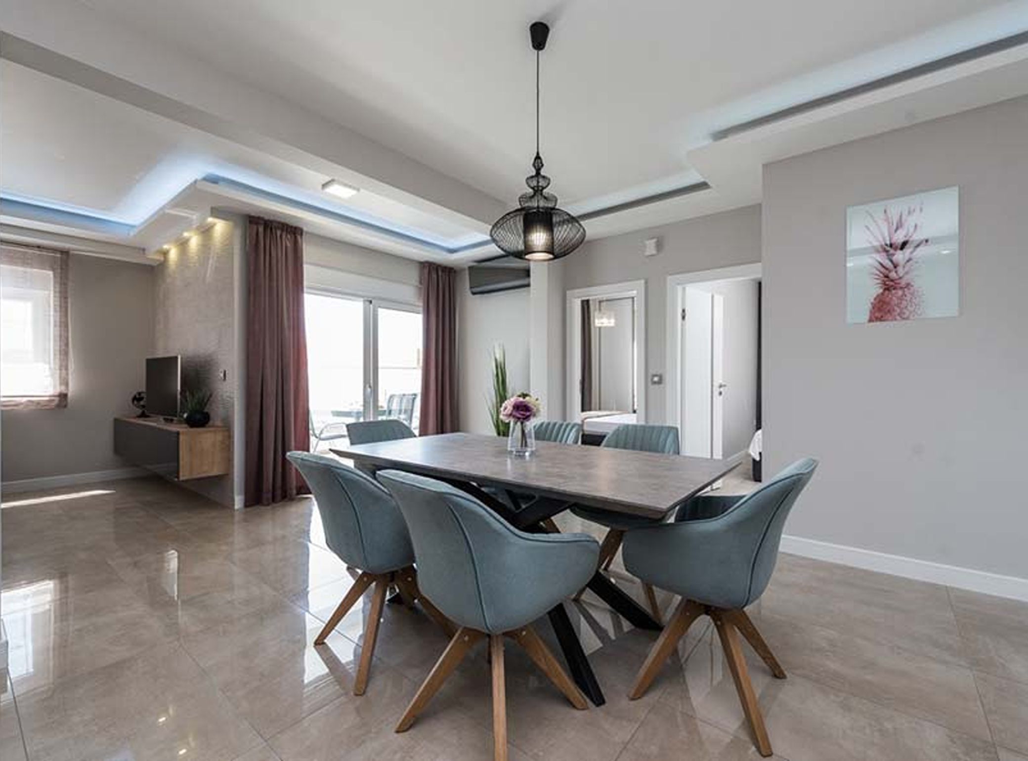 Uma área de refeições moderna com uma mesa grande, quatro cadeiras e um lustre.