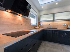 Eine moderne Küche mit Holzarbeitsplatte, schwarzen Schränken, einem eingebauten Backofen und einem Fenster, das für natürliches Licht sorgt.