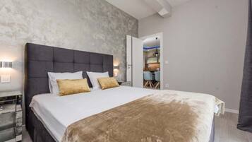 A modern bedroom with a large bed, a nightstand, and a wardrobe.