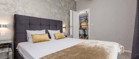 Un dormitorio moderno con una cama grande, una mesita de noche y un armario.