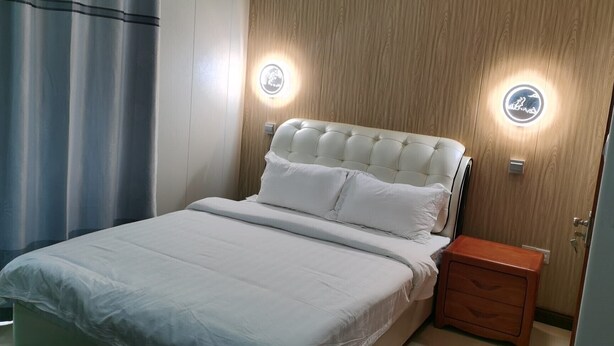 Un letto rifatto con cura, con testiera capitonata, due comodini e illuminazione a parete.
