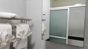 Un bagno con piastrelle bianche, un porta asciugamani con due asciugamani e una cabina doccia in vetro.