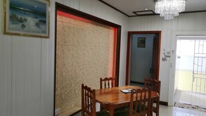 Zona pranzo con tavolo e sedie in legno, un pannello decorativo di grandi dimensioni e un lampadario.