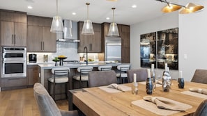 Una cocina moderna con electrodomésticos de acero inoxidable, una isla central e iluminación colgante.