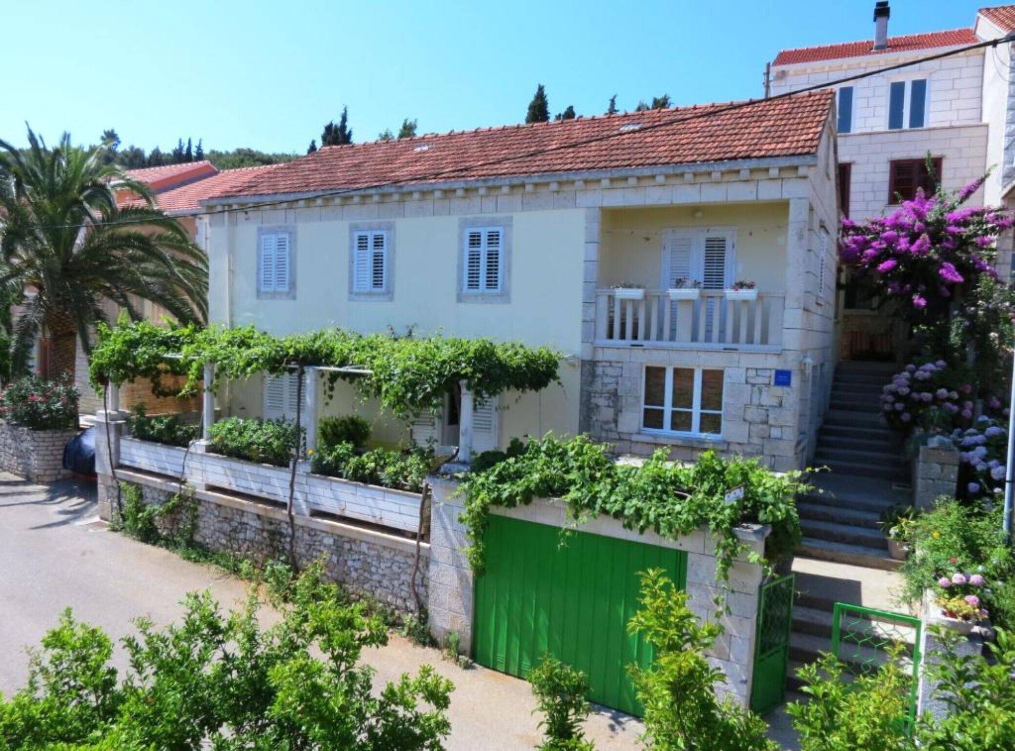 Un edifici de dues plantes amb teulada vermella, persianes blanques i porta verda.