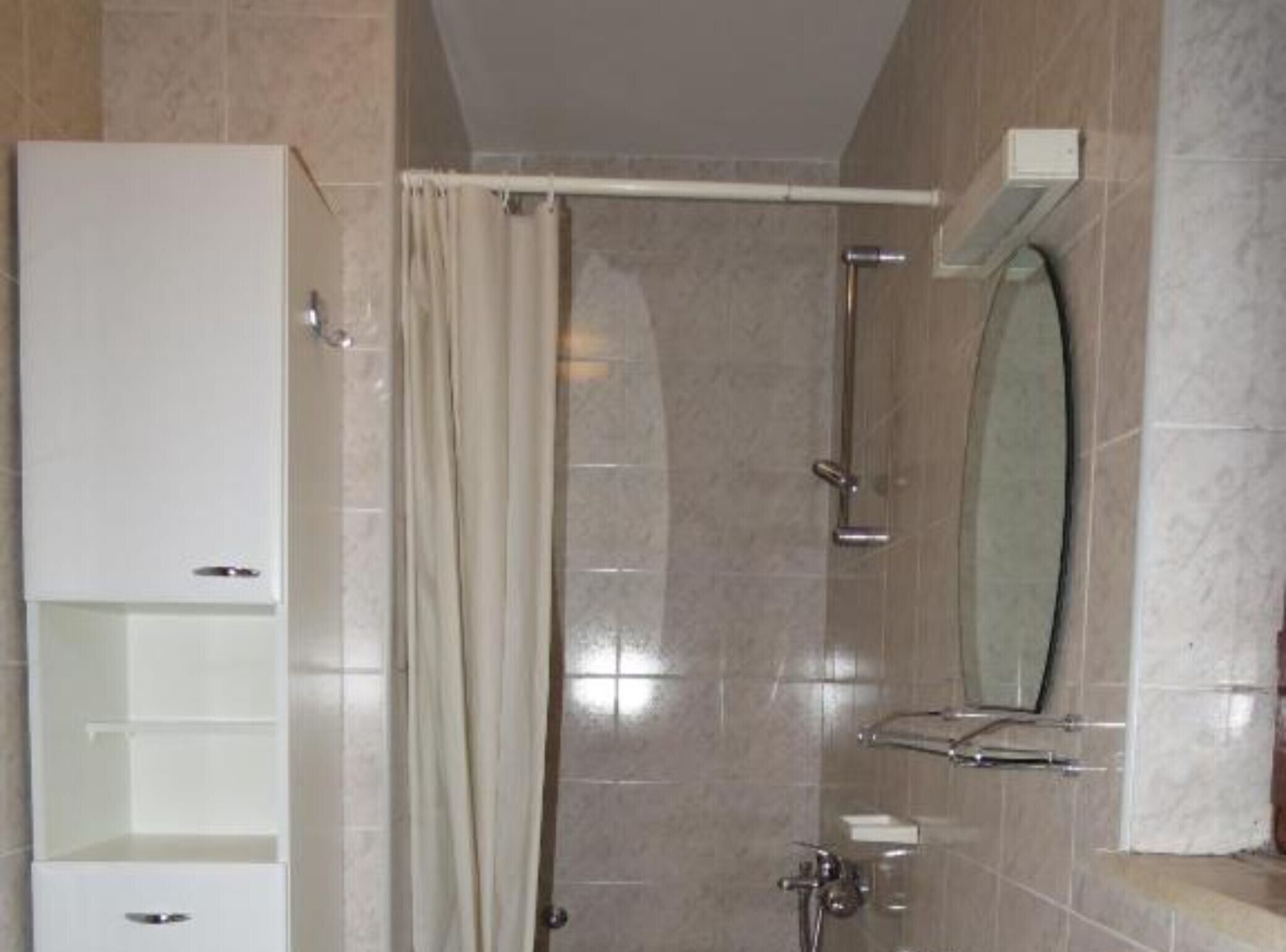 A bathroom with a shower, a mirror, and a cabinet.