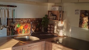 Uma cozinha moderna com armários de madeira, uma pia de aço inoxidável e diversos utensílios de cozinha pendurados em um suporte.