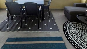 Ein Balkon mit Tisch, Stühlen, einer Couch und einem gemusterten Teppich.