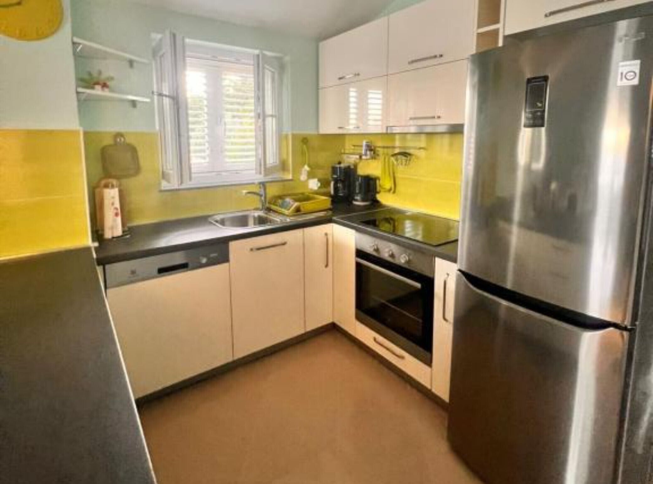 A compact kitchen with a stainless steel refrigerator, a built-in oven, and a sink.