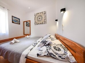 Una cama bien hecha con una colcha estampada, un cabecero de madera y un gran adorno decorativo en la pared superior.