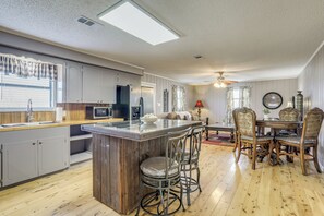 Une cuisine dotée d’un îlot central, de tabourets de bar, d’un plancher en bois et d’un coin repas avec une table et des chaises.