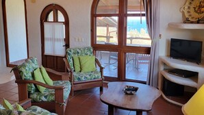 A room with wooden furniture, a ceiling fan, a TV, and large windows. - Casa Altavista 3 Bedroom 4 Bath Oceanview Home with 2 Pools, Patios, and Balconies (San Juan del Sur)