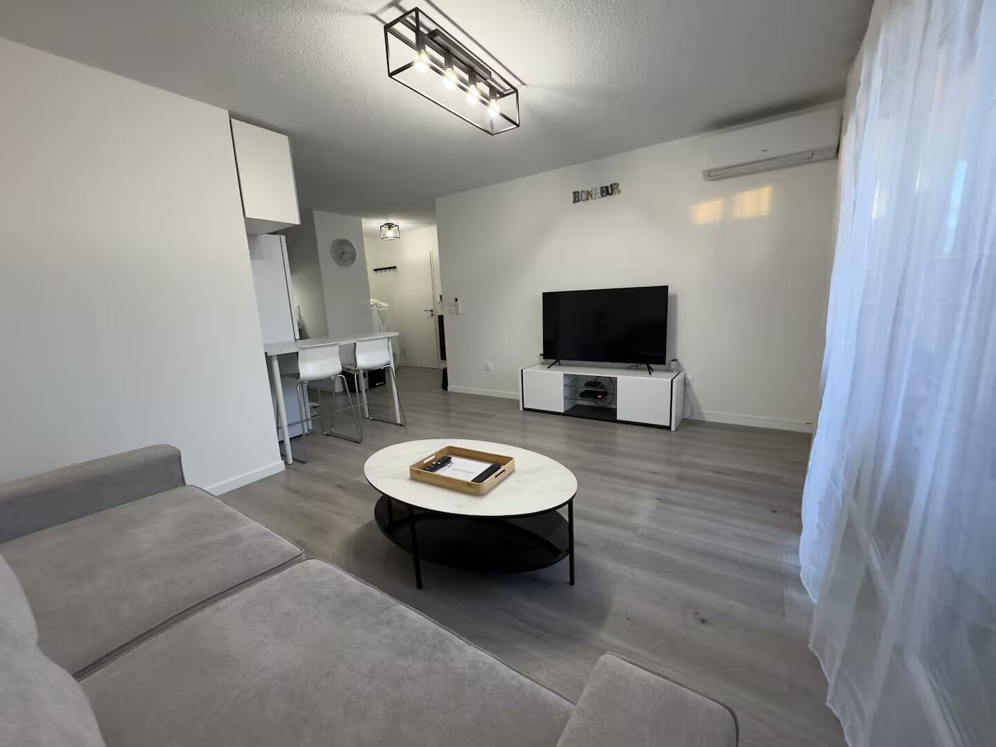 Een moderne woonkamer met een flatscreen televisie, een ronde salontafel en een bank.