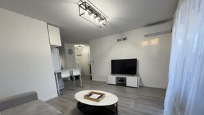 Ein modernes Wohnzimmer mit Flachbildfernseher, rundem Couchtisch und einer Couch.