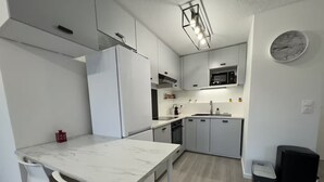 Eine moderne Küche mit weißen Schränken, einer Marmorarbeitsplatte und einem schwarzen Mülleimer.