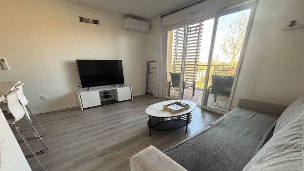 Ein modernes Wohnzimmer mit Flachbildfernseher, rundem Couchtisch und einer Couch.