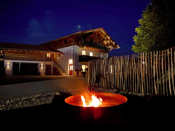 A two-story house with a fire pit in the foreground.