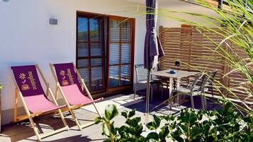 Un balcon avec une table et des chaises, une porte-fenêtre coulissante et le chiffre « 3 » peint sur le mur.