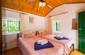 A room with two beds, a wooden ceiling, and a green door. - Marguerita House in Paxi (Paxi)