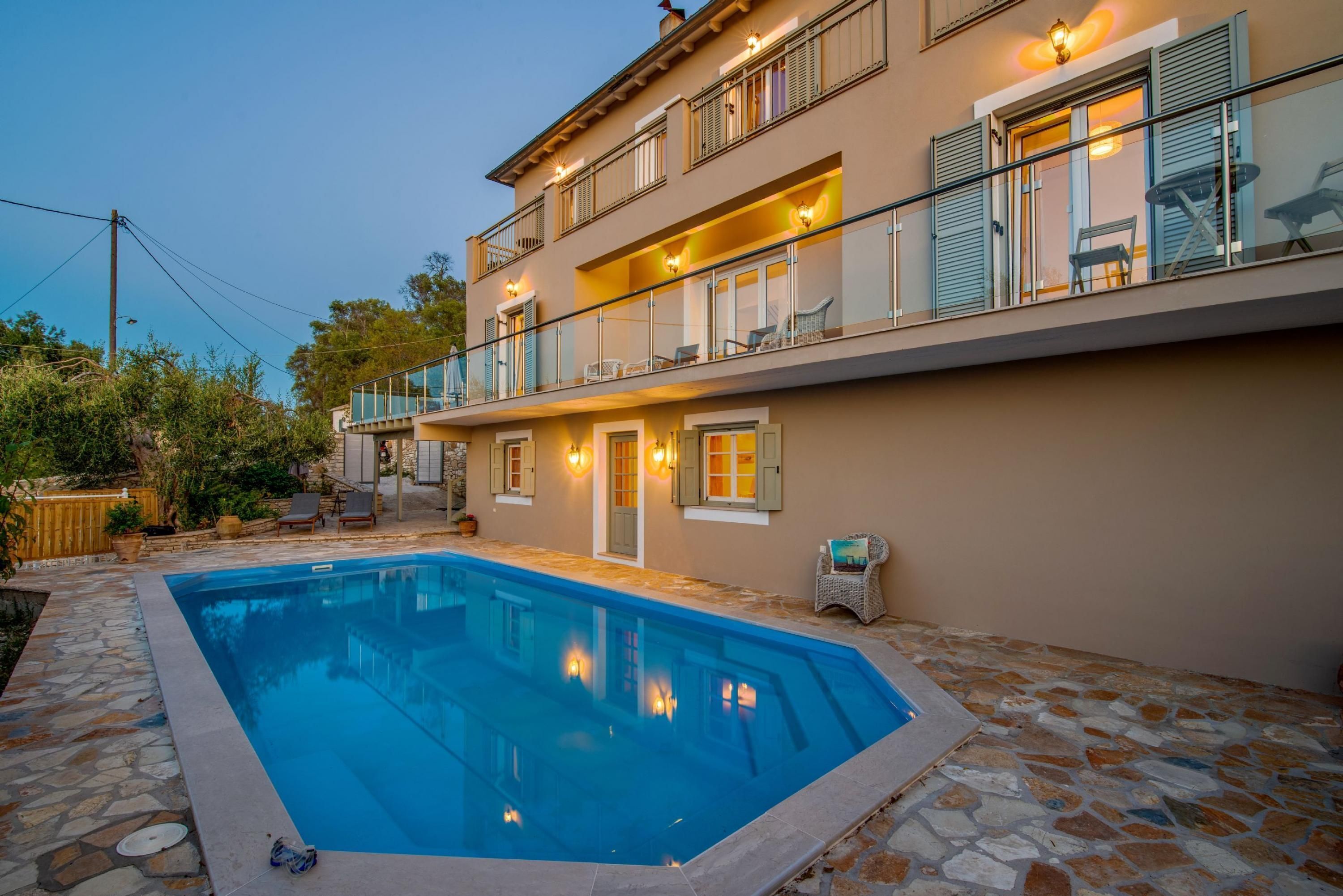 A two-story building with a swimming pool, outdoor seating, and a balcony with lights.