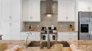 Una cocina moderna con armarios blancos, estufa de acero inoxidable y horno empotrado.