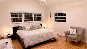 Un dormitorio con una cama, una silla y dos ventanas.