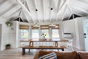 A dining area with a wooden table, white chairs, and hanging pendant lights.