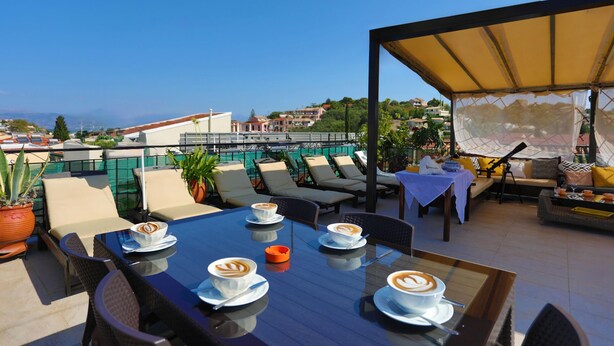 Terraço no telhado com área de estar ao ar livre, mesa com xícaras de café e vista para a paisagem urbana.