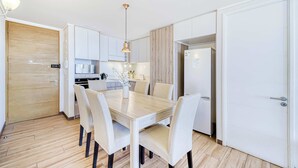 Una cocina moderna con armarios blancos, una mesa de comedor de madera con seis sillas y una lámpara colgante.